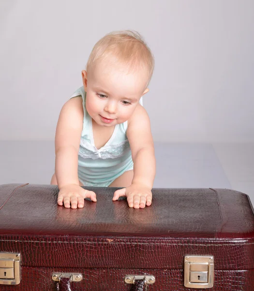 Menina brincando com mala no fundo cinza — Fotografia de Stock