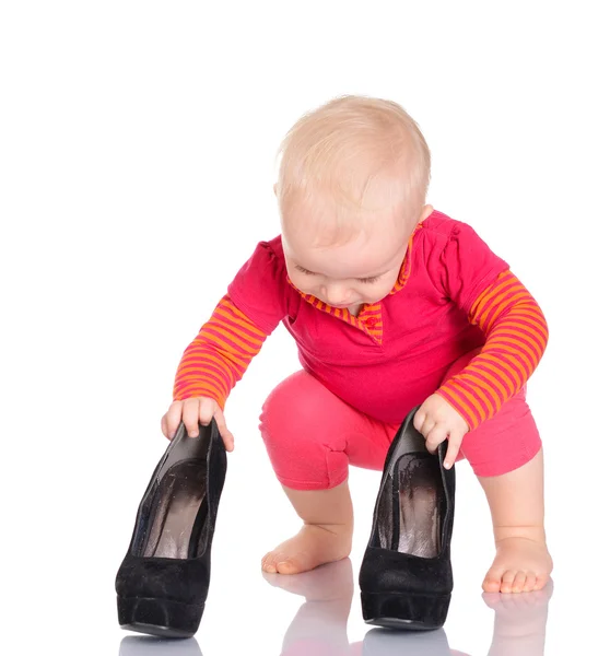 Bonito pouco bebê menina tentando no ela mãe 's sapatos no branco de volta — Fotografia de Stock