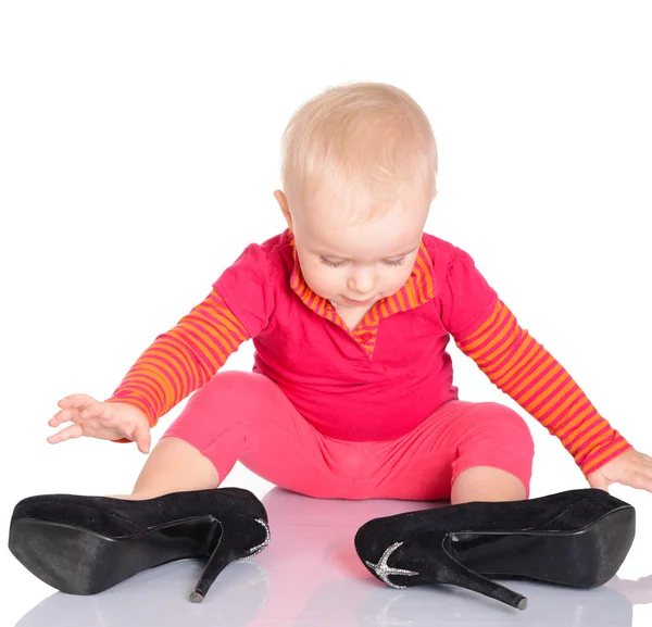 Cute little baby girl trying on her mother's shoes on white back — Stock Photo, Image