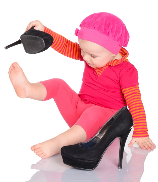 Cute little baby girl trying on her mother's shoes on white back — Stock Photo, Image