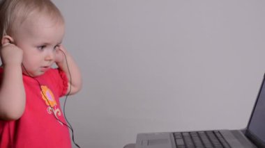 dizüstü bilgisayar kullanan şirin bebek kız kulaklıktan koyar. raf odak ve dolly