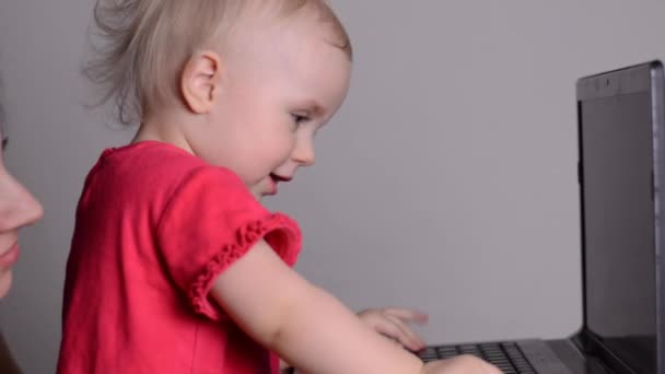 Linda niña usando una computadora portátil. Concentración en bastidor y muñeca en . — Vídeos de Stock