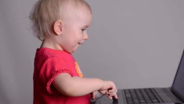 Menina bonito usando um computador portátil coloca em fones de ouvido. Rack foco e boneca — Vídeo de Stock