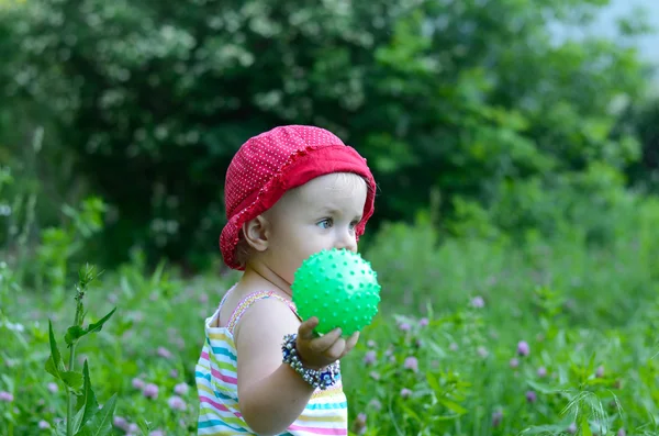 Cute little girl sitting in the green field — Stock Photo, Image