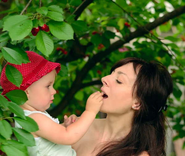 Baby with mother, cherry tree background — Stock Photo, Image