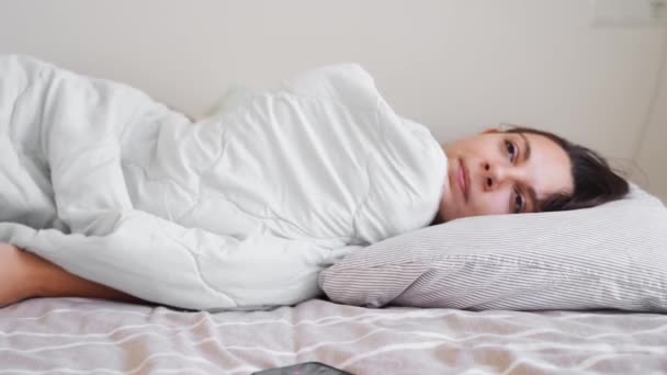 Giovane donna va a dormire Dipendenza dal telefono, insonnia. Cerca di addormentarti. Tracciamento del sonno al telefono. Ritmo circadiano. — Video Stock