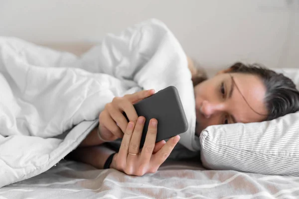 La joven se duerme. Adicción al teléfono, insomnio. Intenta dormirte. Seguimiento del sueño en el teléfono. Ritmo circadiano. — Foto de Stock