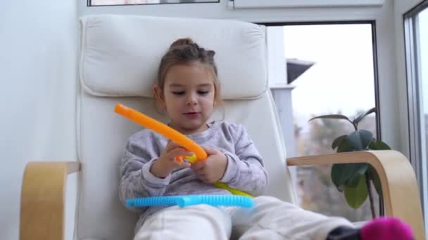 Menina feliz pré-escolar brincando com tubo pop. Nova moda anti stress fidget. Aliviador de estresse, desenvolvimento de habilidades motoras para crianças. — Vídeo de Stock