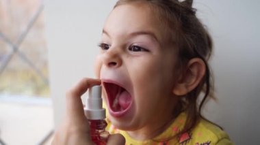 Anaokulunda sprey tedavisi gören bir kız. Bronşit tedavisi evde. solunum hastalığı ilacı