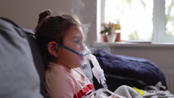 Sick adorable preschool girl with nebuliser mask at home. Treatment for bronchitis with inhaling medicine nebula. — Stock Video