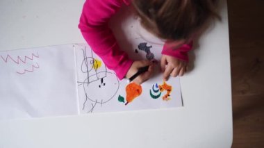 Renkli kalemlerle resim çizen küçük kız. Anaokulu öğrencisi evde eğitim görüyor. Yaratıcılık becerileri geliştiriyor.