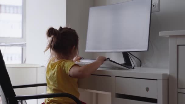 Dziecko w przedszkolu w domu za pomocą komputera. Biuro domowe z małymi dziećmi w domu. Kocie zwierzę z dziećmi. Praca w domu podczas kwarantanny. — Wideo stockowe