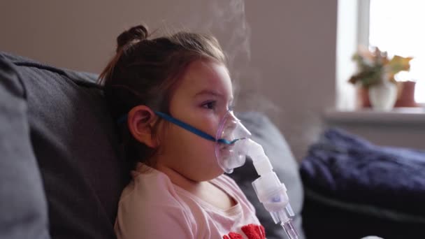 Sick adorable preschool girl with nebuliser mask at home. Treatment for bronchitis with inhaling medicine nebula. — Stock Video