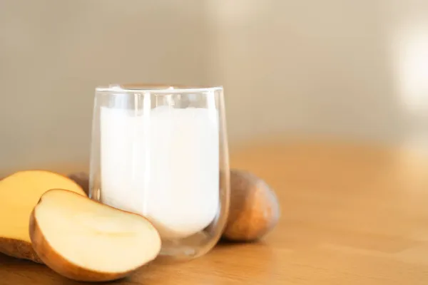 木製の背景にジャガイモのミルク写真。代替牛乳のガラス.植物由来のベジタリアン飲料。飲み放題 — ストック写真