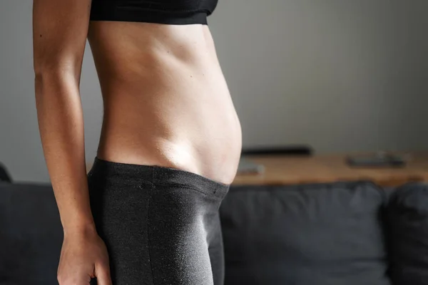 Mujer joven vista lateral del cuerpo. Vientre hinchado. Embarazo. Diastasis recti después del parto. Ejercicios de fitness y dieta para bajar de peso. — Foto de Stock