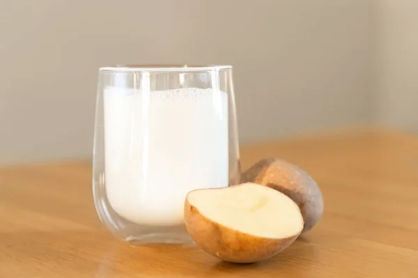 Foto de leche de patata sobre fondo de madera. Un vaso de leche alternativa. Bebida vegetariana de origen vegetal. Bebida sin lactosa —  Fotos de Stock