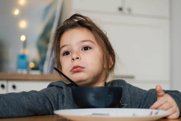 Menina bonita come sopa de tigela preta com pão e cebola. Estilo de vida foto de criança na cozinha tendo uma refeição. — Fotografia de Stock