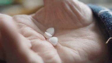 Son sınıf öğrencisinin elinde iki hap tutarken kendini kötü hissettiği ve tedavi gördüğü yakın plan. Eline odaklan. Emekli bir adamın buruşuk eli