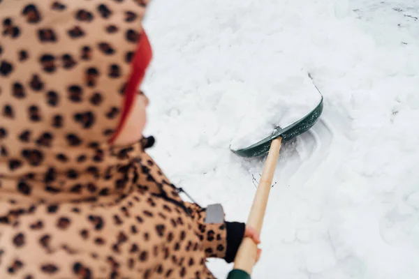 Vista de ángulo bajo de la niña ayudando a limpiar el camino de la nieve con la pala. Niño jugando en el jardín de invierno nevado — Foto de Stock