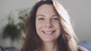 Evinde genç bir kadının mutlu gülümseyen portresi. Ağır çekim. Neşeli ve çekici biri.