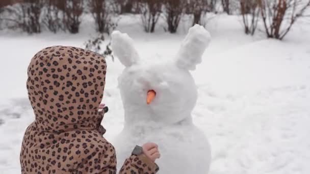 子供は冬の雪の日に遊んでいる。都会の裏庭で家族と一緒に雪だるまを作る. — ストック動画