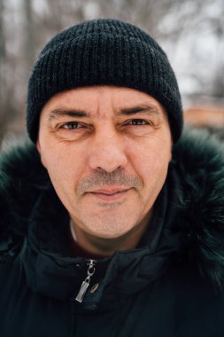 Olgun beyaz erkek portresi. Yakından. Soğuk kış günü ve açık havada siyah, sıcak elbiseli bir adam. 
