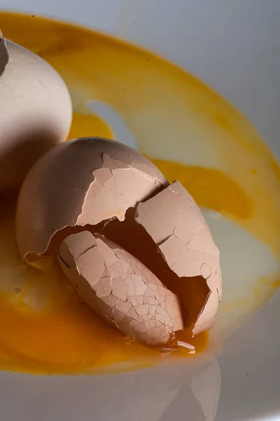 Feltört tojások fehér tányéron, reggeli fényben. Törött tojáshéj — Stock Fotó