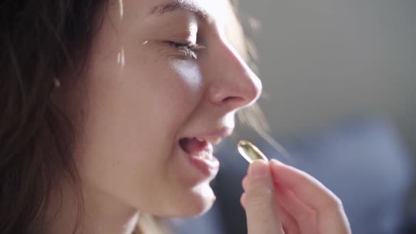 Close-up portret van jonge duizendjarige vrouw het nemen van supplement pillen in de ochtend. Slow motion video van meisje die Omega 3 olie capsule — Stockvideo