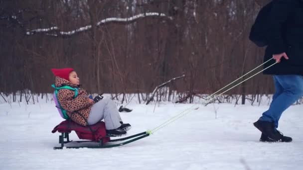Gros plan des jambes des enfants sur les traîneaux à neige. Activité d'hiver en plein air pour les enfants — Video