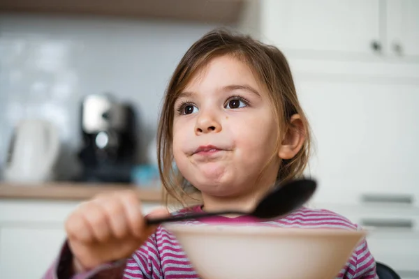 Close up de retrato menina pré-escolar com expressão engraçada comer sopa em casa — Fotografia de Stock