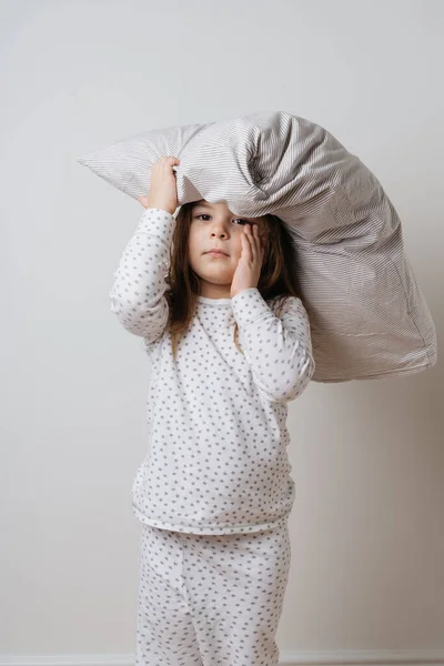 Retrato de chica caucásica bonita en pijama blanco y almohada en fondo blanco estudio —  Fotos de Stock