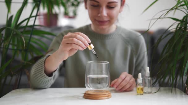 Donna cadere gocce di clorofilla in vetro con acqua, bere bevanda antiossidante. Stile di vita sano — Video Stock