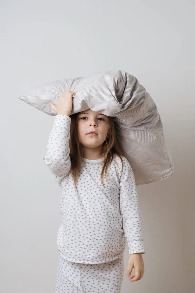 Retrato de chica caucásica bonita en pijama blanco y almohada en fondo blanco estudio —  Fotos de Stock