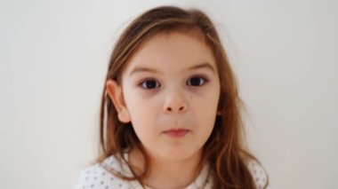 Komik anaokulu kızı aptalca suratlar yapıyor. Duygularıyla samimi bir çocuk portresi yapıyor. Yüksek kalite 4k görüntü