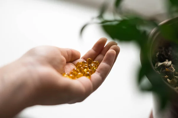 Nahaufnahme einer Hand voller gelber Softbälle. Die Einnahme von Nahrungsergänzungsmitteln, Vitamin D oder Omega. Wellness Biohacking-Konzept — Stockfoto