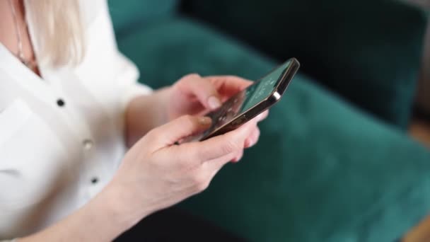 Zamknij ręce kobiety z nagim lakierem do paznokci za pomocą smartfona w domu. Zielona sofa tło. — Wideo stockowe