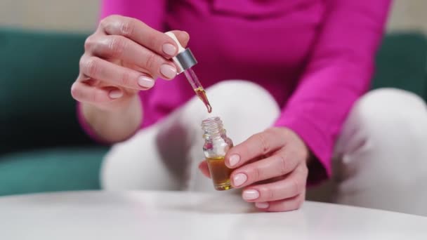 Cierre las manos de mujer con botella de gotitas de vidrio de aceites esenciales. Bienestar remedios naturales. — Vídeo de stock