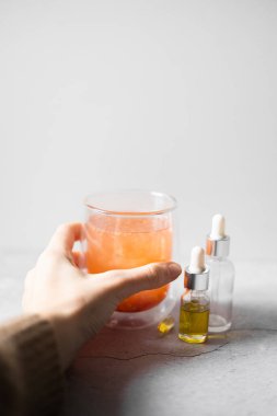 Gerekli yağ ve tıbbi çay içeren cam damlatıcı şişesi, gri arka planda omega kapsülü. Homeopati kavramı