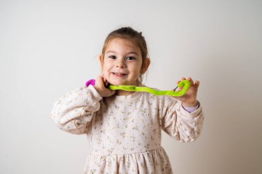 Mutlu küçük kız beyaz arka planda oyuncak çiçeklerle oynuyor