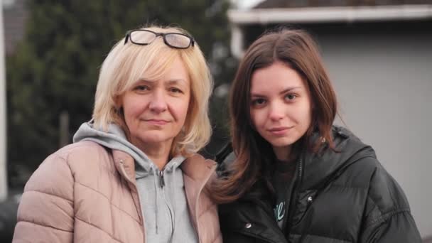 Volwassen moeder en jonge dochter videoportret samen buiten op een winderige koude dag. Blank blond en bruin haar vrouwen — Stockvideo