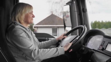 Beyaz, orta yaşlı bir kadın kamyon kullanıyor. Kamyoncu kadın işçi, taşımacılık endüstrisi işgali. 