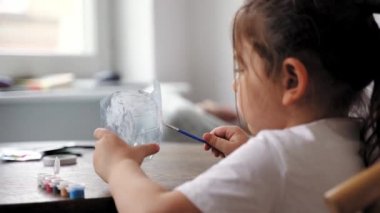 Kafkasyalı anaokulu kızı plastik şişe ve boyalarla el işi yapıyor. Geri dönüşüm atıkları. Sürdürülebilir yaşam tarzı