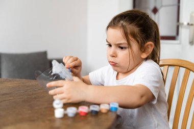 Kafkasyalı anaokulu kızı plastik şişe ve boyalarla el işi yapıyor. Geri dönüşüm atıkları. Sürdürülebilir yaşam tarzı