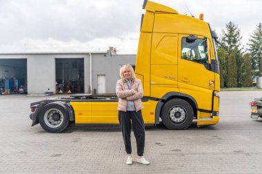 Beyaz, orta yaşlı bir kadın kamyon kullanıyor. Kamyoncu kadın işçi, taşımacılık endüstrisi işgali. 