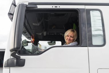 Beyaz, orta yaşlı bir kadın kamyon kullanıyor. Kamyoncu kadın işçi, taşımacılık endüstrisi işgali. 