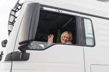 Beyaz, orta yaşlı bir kadın kamyon kullanıyor. Kamyoncu kadın işçi, taşımacılık endüstrisi işgali. 