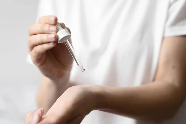 Primer plano de la mano de mujer blanca aplicando aceite de aceite esencial o suero para la piel. Concepto de autocuidado — Foto de Stock