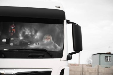 Beyaz, orta yaşlı bir kadın kamyon kullanıyor. Kamyoncu kadın işçi, taşımacılık endüstrisi işgali. 