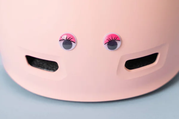 Casco rosa con divertidos ojos de muñeca sobre fondo azul. Niños al aire libre actividad seguridad protección — Foto de Stock