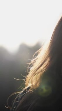 Kadın saçı, rüzgar ve günbatımı güneşi, yumuşak odaklı el kamerası videosu. Özgürlük ve rahatlama kavramı